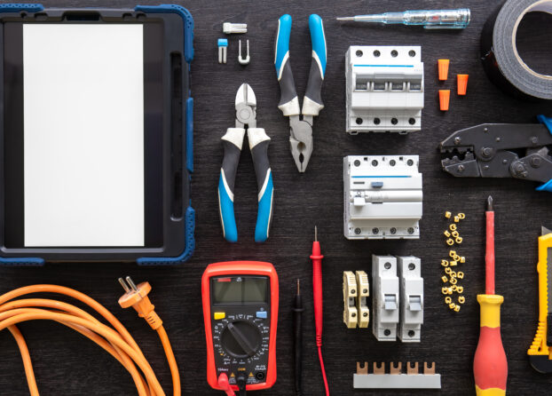 Different electrical tools on wooden background, flat lay.